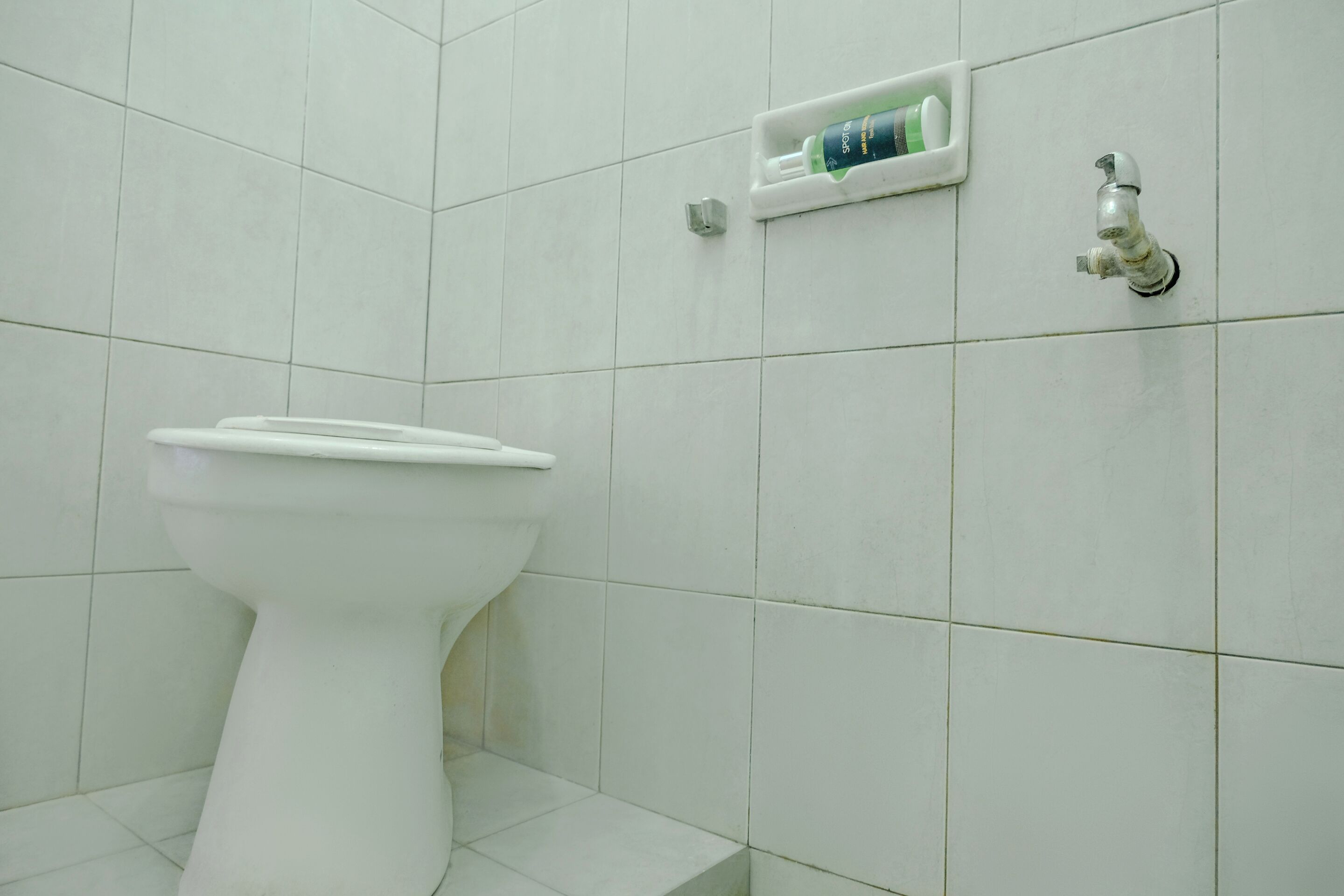 A white toilet in a bathroom with white tiles.