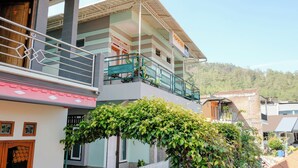 Un edificio de varios pisos con un balcón, una cerca blanca de piquetes y una enredadera verde exuberante.