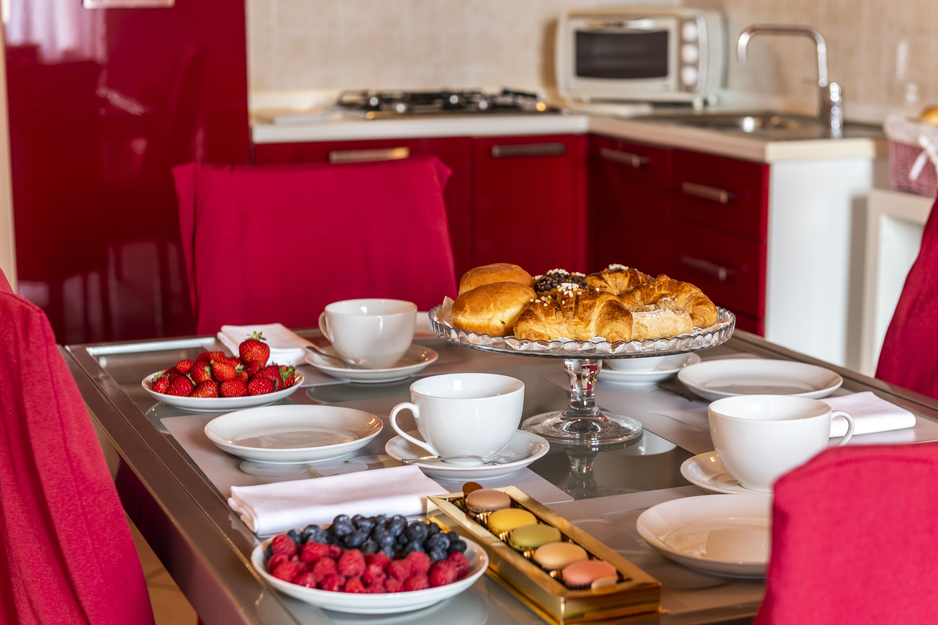 A breakfast setting with pastries, fruits, and coffee cups on a table.