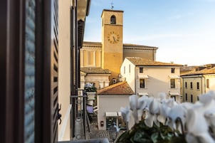 Una torre dell'orologio con una campana, circondata da edifici dall'architettura tradizionale.