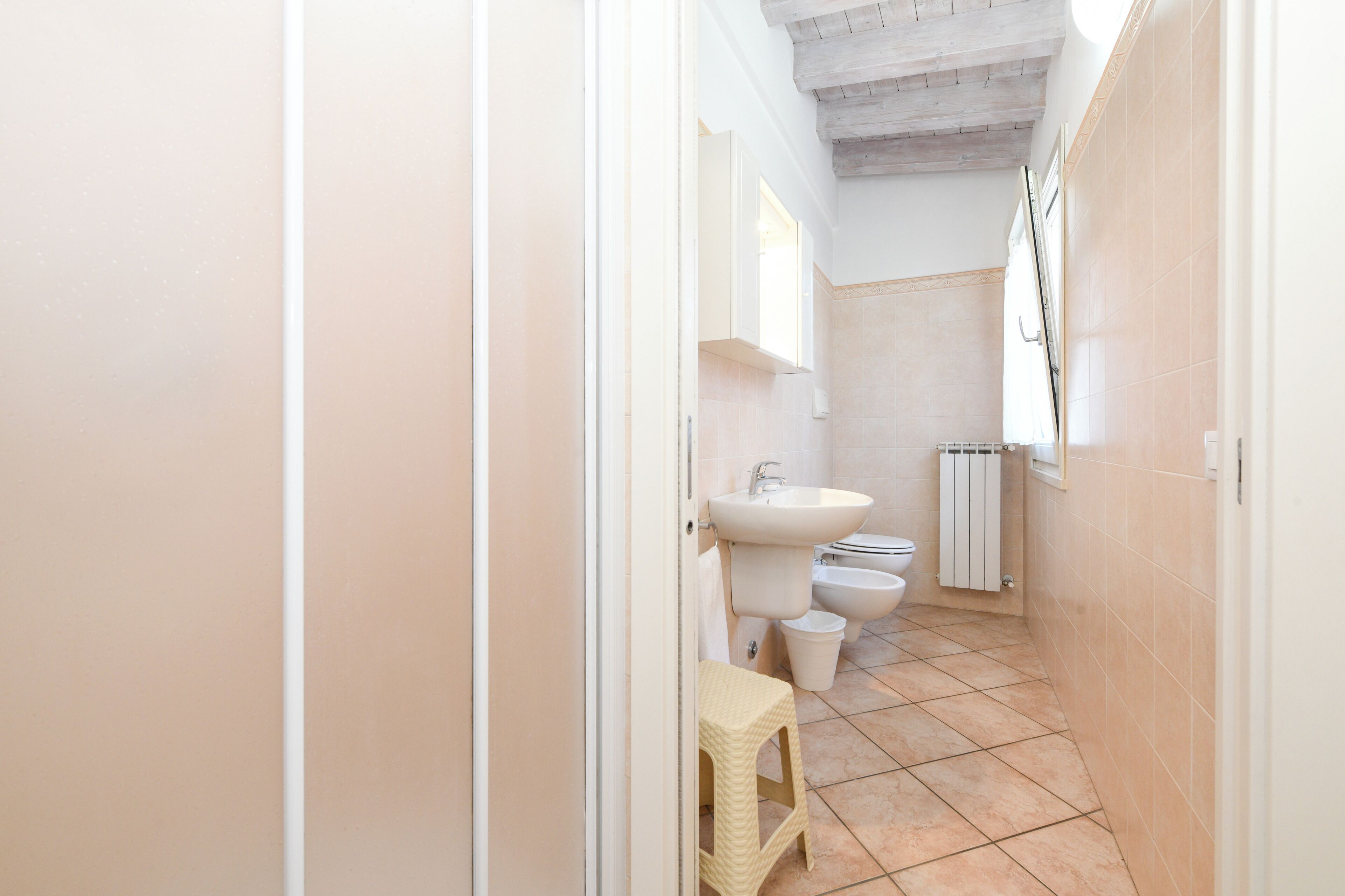 Une petite salle de bain comprenant un lavabo, deux toilettes et un petit tabouret.