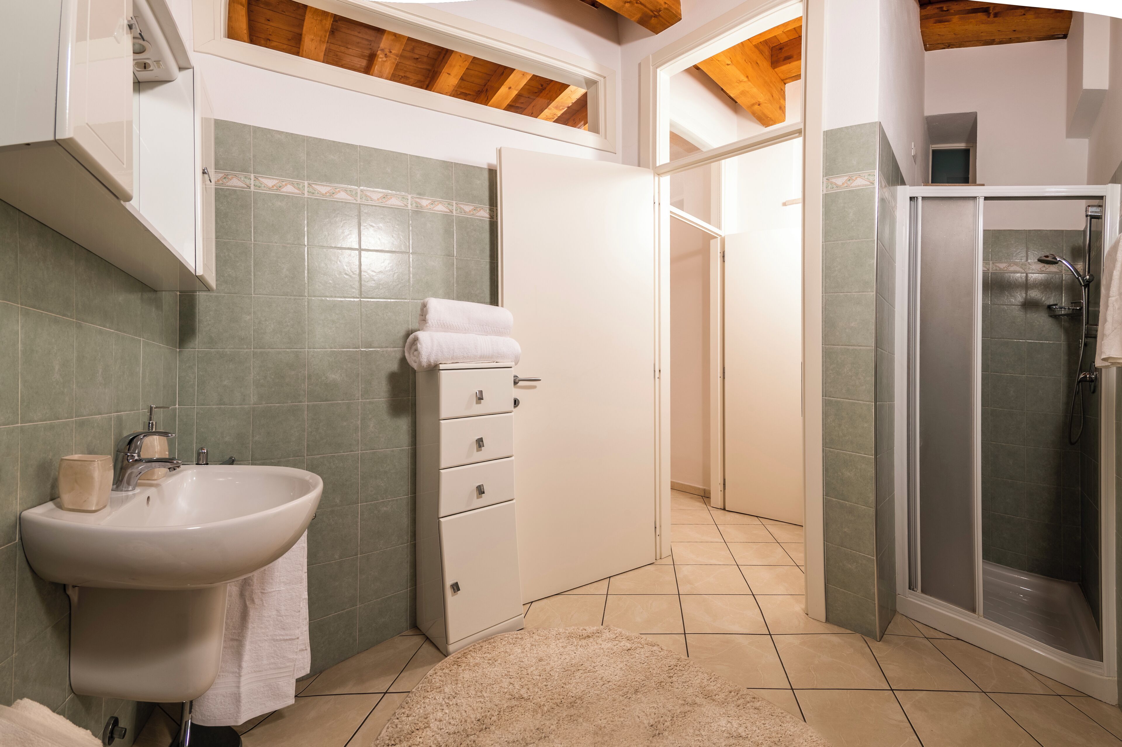 Een badkamer met een wastafel, kast en douche.
