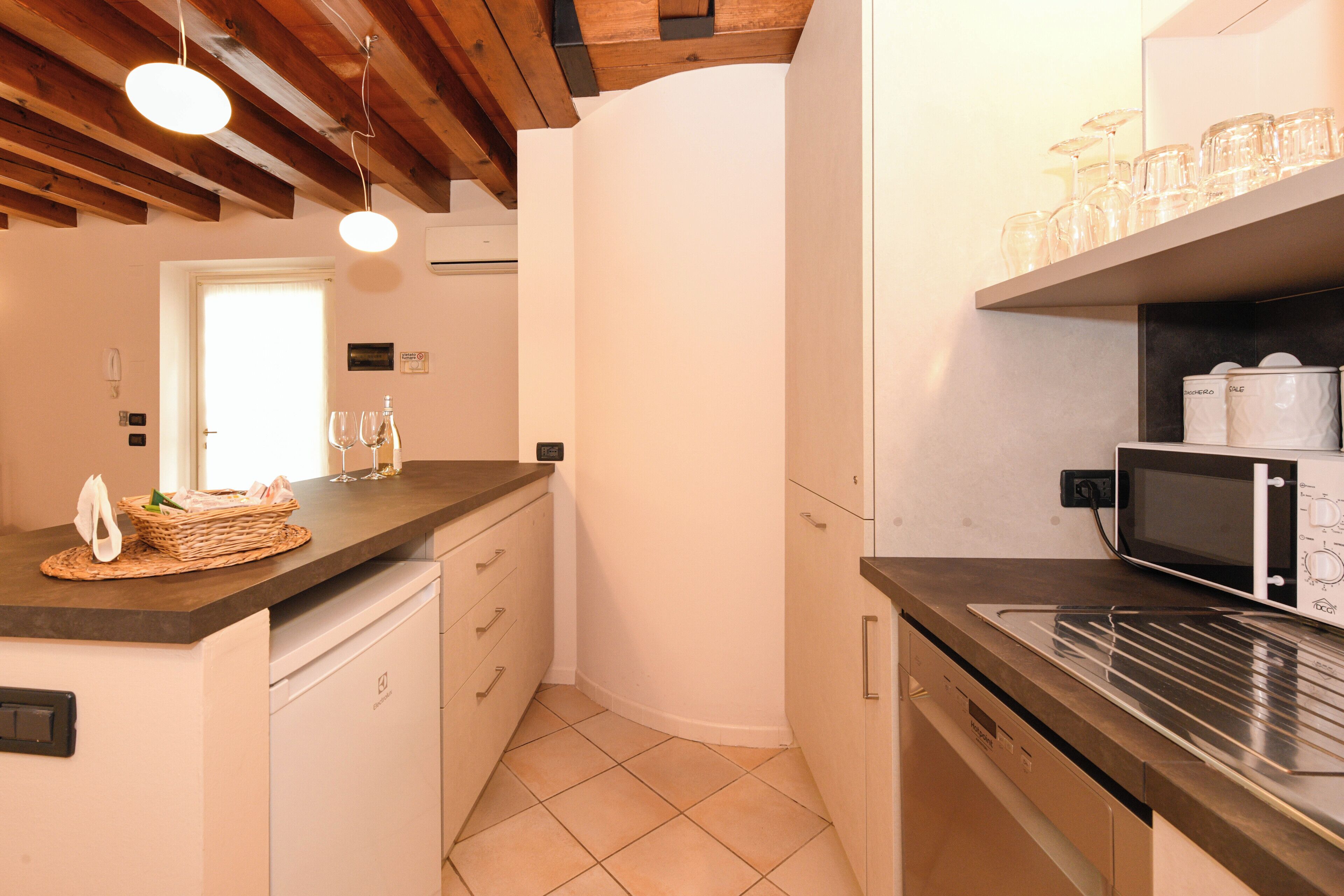 A kitchen with a microwave, a sink, and a countertop with glassware.