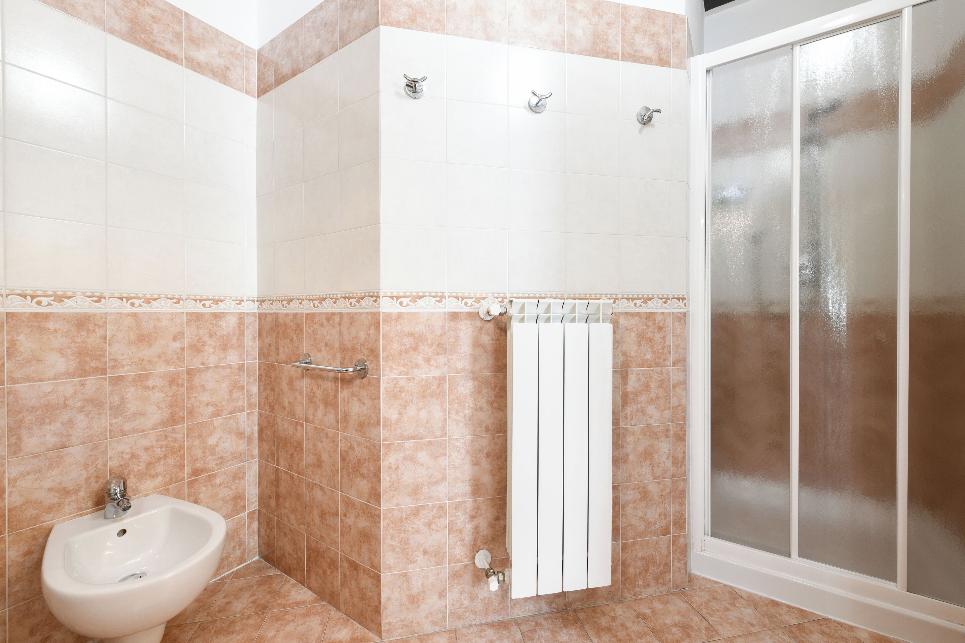 Une salle de bain équipée d’un bidet, d’un porte-serviettes et d’une cabine de douche.