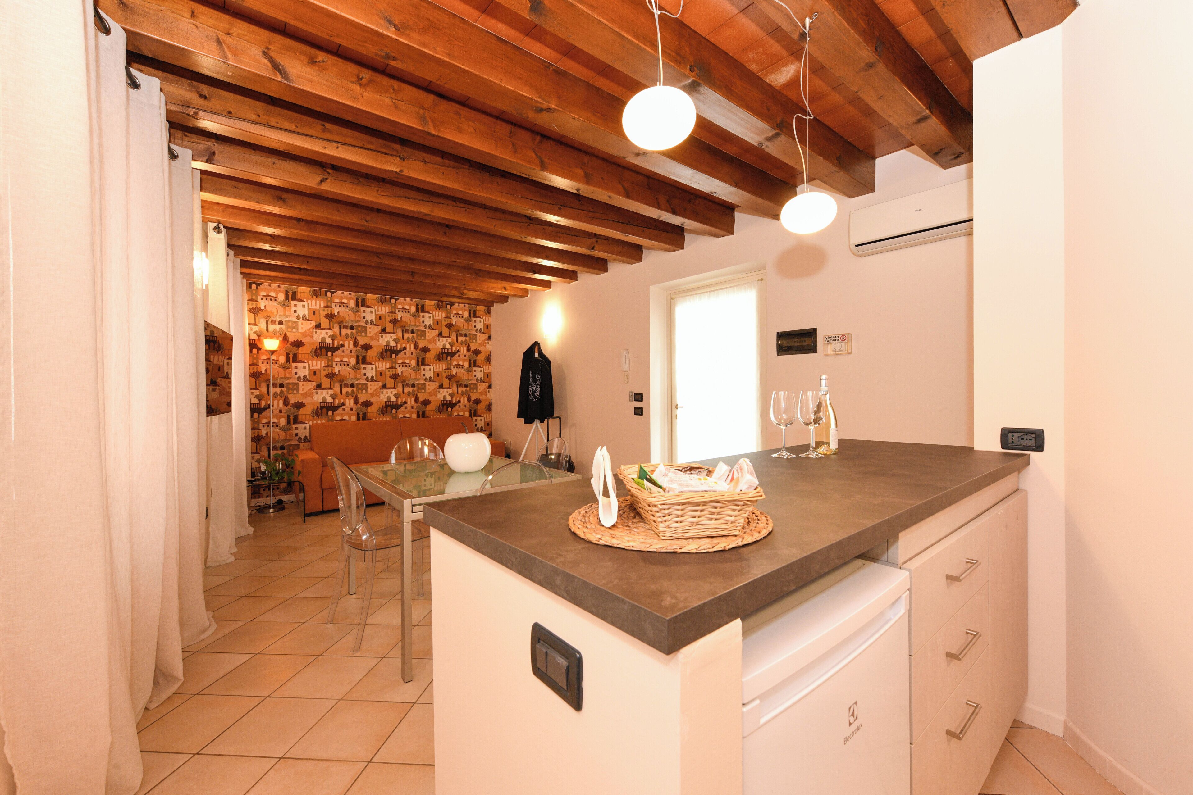 Una cucina con travi in legno, un'area pranzo con parete decorata e un frigorifero bianco.