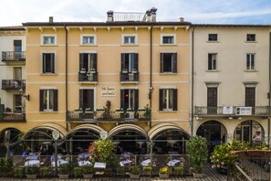 A building with multiple balconies, outdoor seating, and a sign for "B&B Flowers Apartments." - Flowers Apartments (Desenzano del Garda)