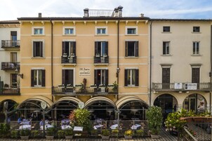 Un edificio con numerosi balconi, arredi esterni e un cartello che indica "B&B Flowers Apartments".