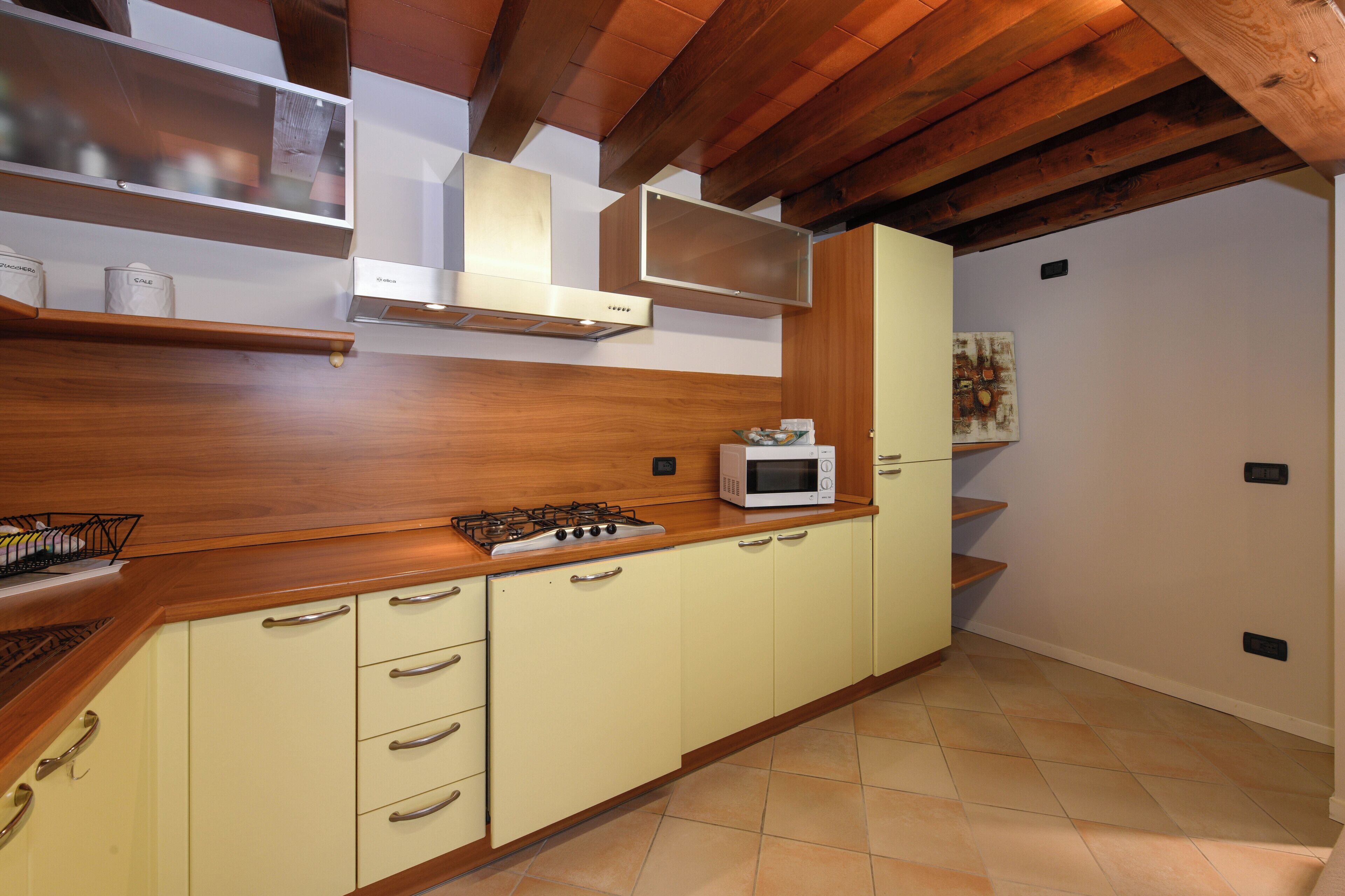 A kitchen with wooden cabinets, a gas stove, a microwave, and a hanging range hood.