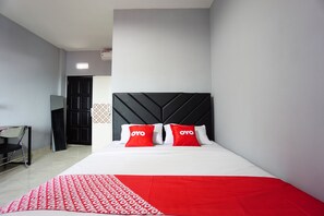 Ein Hotelzimmer mit Bett, Fernseher und Schreibtisch.
