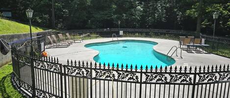 Une piscine ronde, agrémentée d’une clôture décorative, entourée de verdure.