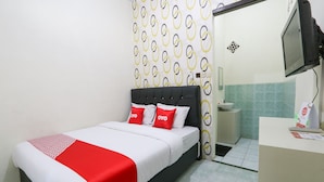 Habitació d'hotel amb un llit, una taula de nit, una televisió i un bany visible a través d'una porta oberta.