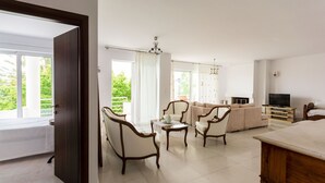 A spacious living room with a sofa set, armchairs, a coffee table, and a TV. - Roof garden Seaside lux Home (Chania)