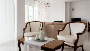 A living room with a sofa, two armchairs, a coffee table, and a television. - Roof garden Seaside lux Home (Chania)