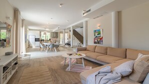 A spacious living area with a sofa, a dining table, and a kitchen in the background.