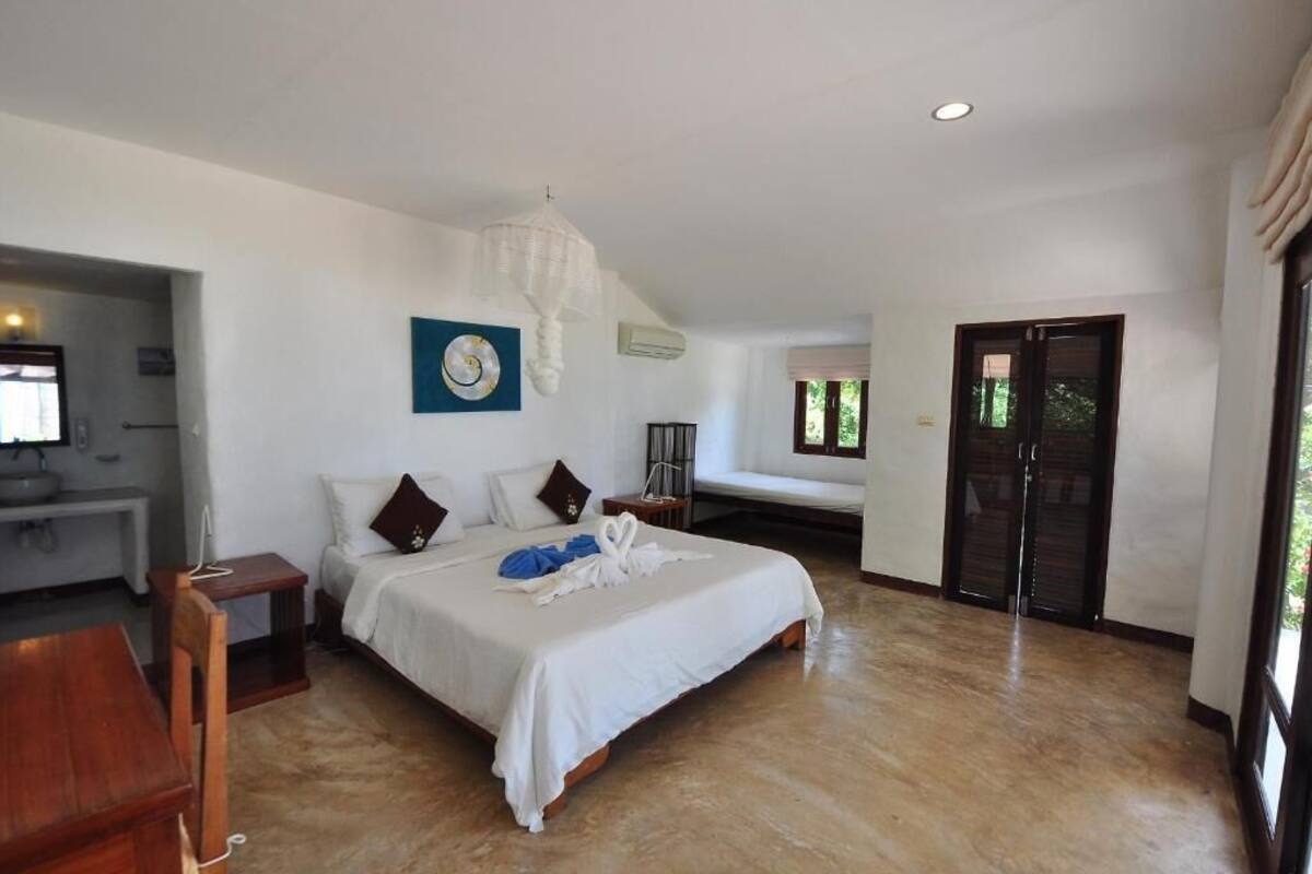 A spacious bedroom with a large bed, a bedside table, a chair, and a desk.