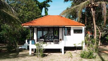 Un edificio blanco con techo rojo, rodeado de palmeras y follaje.
