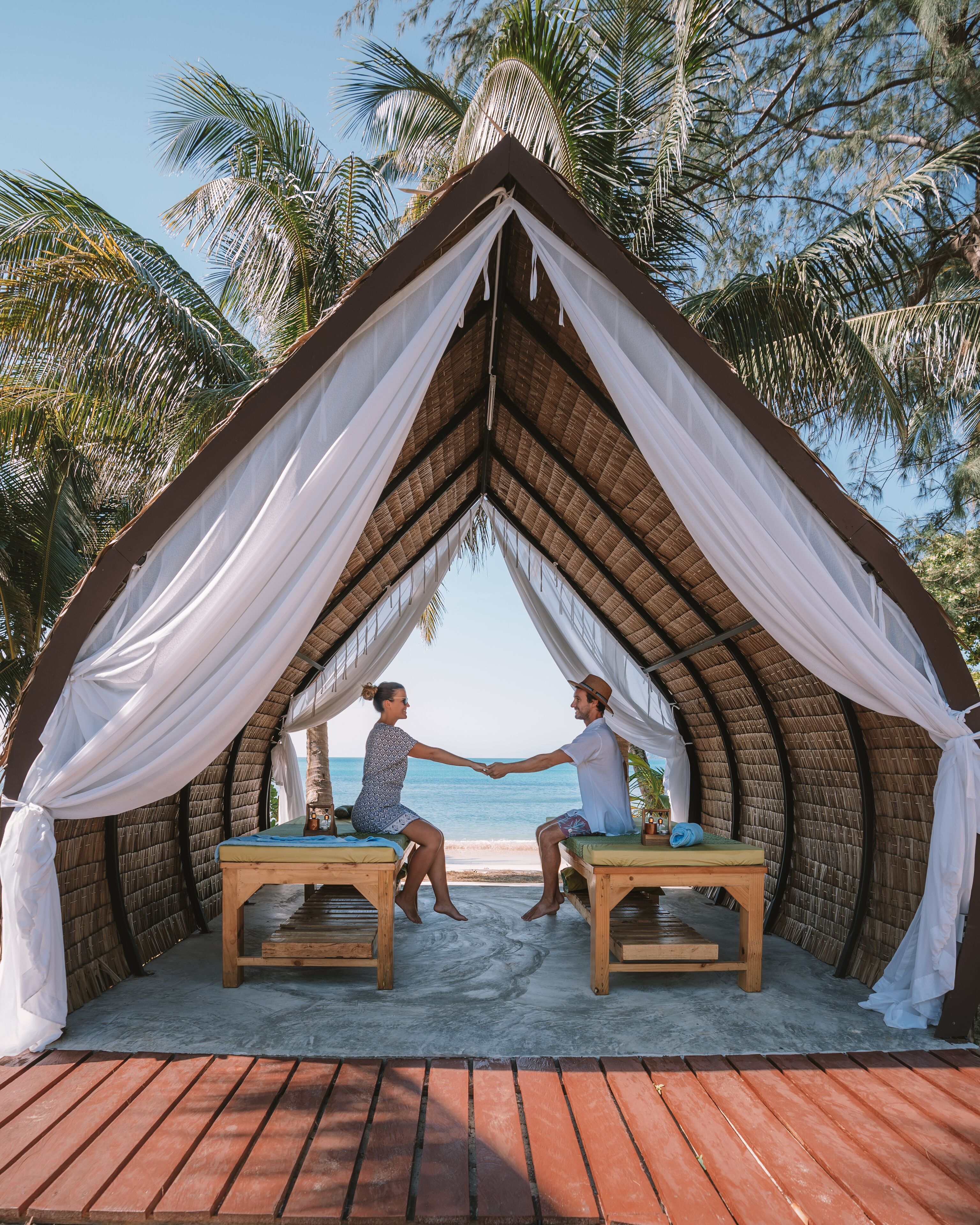 A thatched-roof gazebo with white drapes, two wooden benches, and a view of the ocean. - Lazy Day The Resort (Ko Mak)
