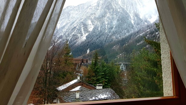 Une vue sur la montagne, visible depuis une fenêtre à cadre en bois.