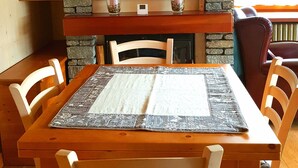 Un coin repas agrémenté d’une cheminée en pierre, d’un tableau encadré et d’une table avec un set de table.