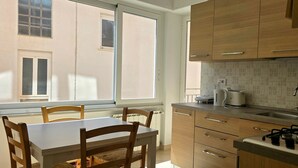 A kitchen with wooden cabinets, a gas stove, a sink, and a window. - Monterosso Apartment (Monterosso al Mare)