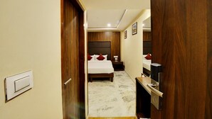 A hotel room with a bed, bedside table, and a TV. - Manpho Bell Hotel & Convention Center (Bengaluru)
