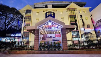 A hotel entrance with a prominent sign reading "Manpho Bell Hotel & Convention Center".