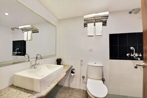 A bathroom with a sink, mirror, toilet, and towel rack. - Manpho Bell Hotel & Convention Center (Bengaluru)