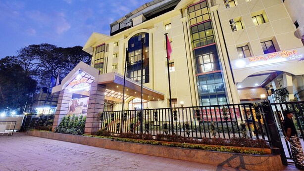 A multi-story hotel with a modern facade, large windows, and a well-lit entrance area. - Manpho Bell Hotel & Convention Center (Bengaluru)