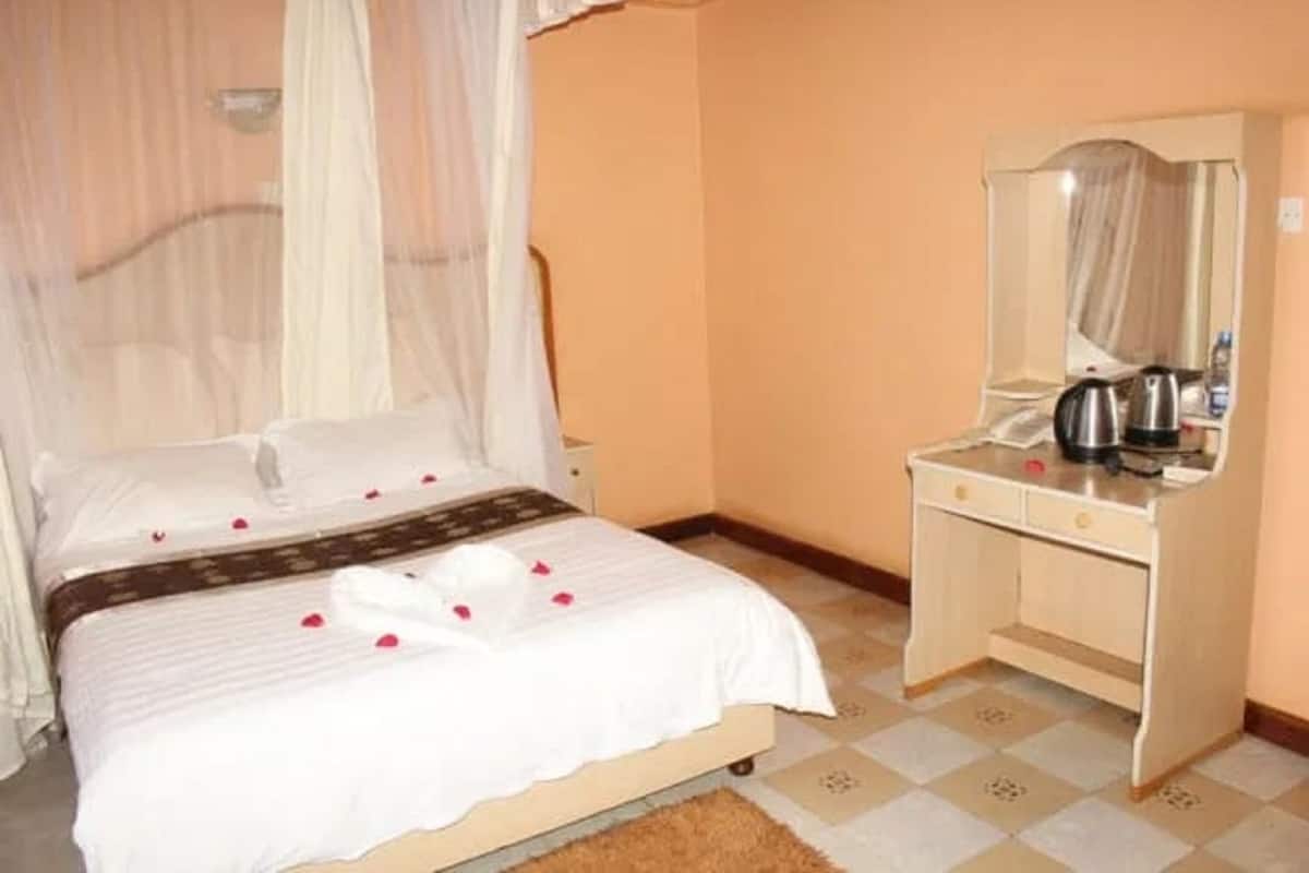 Une chambre à coucher avec un lit, une table de chevet, un miroir et un petit bureau.