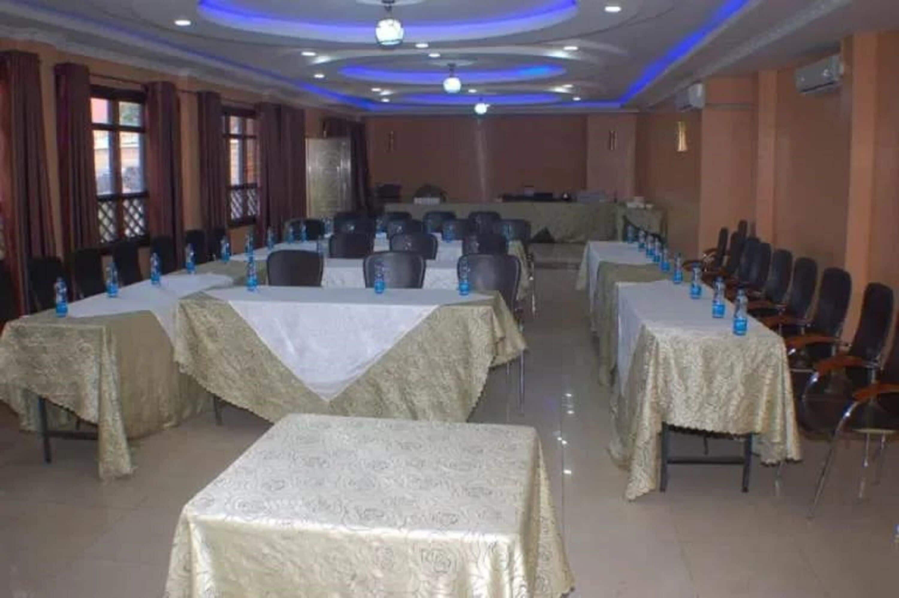 A conference room with tables covered in white tablecloths, arranged in rows with chairs.