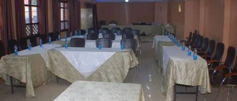 A conference room with tables covered in white tablecloths, arranged in rows with chairs.