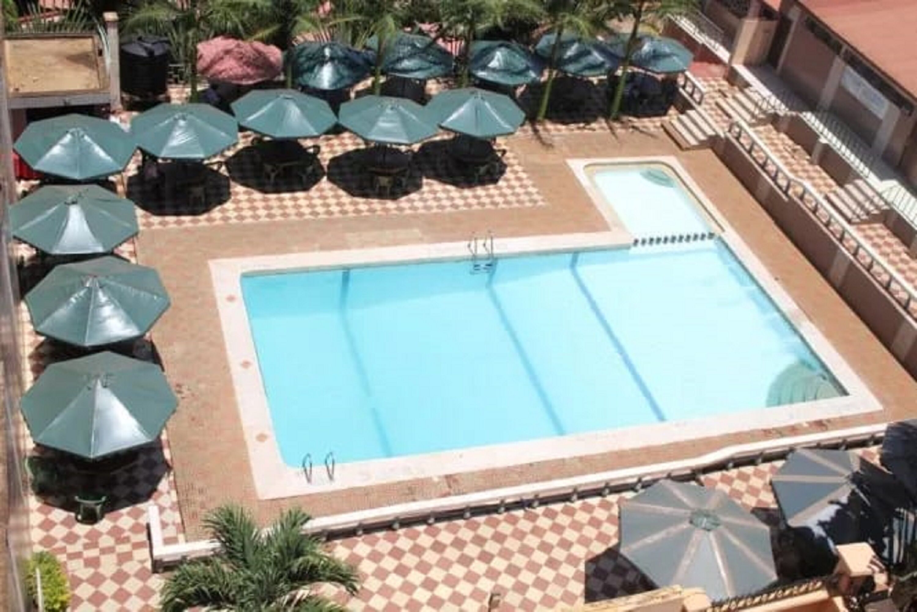 A swimming pool with a checkered floor pattern, surrounded by umbrellas and lounge chairs.