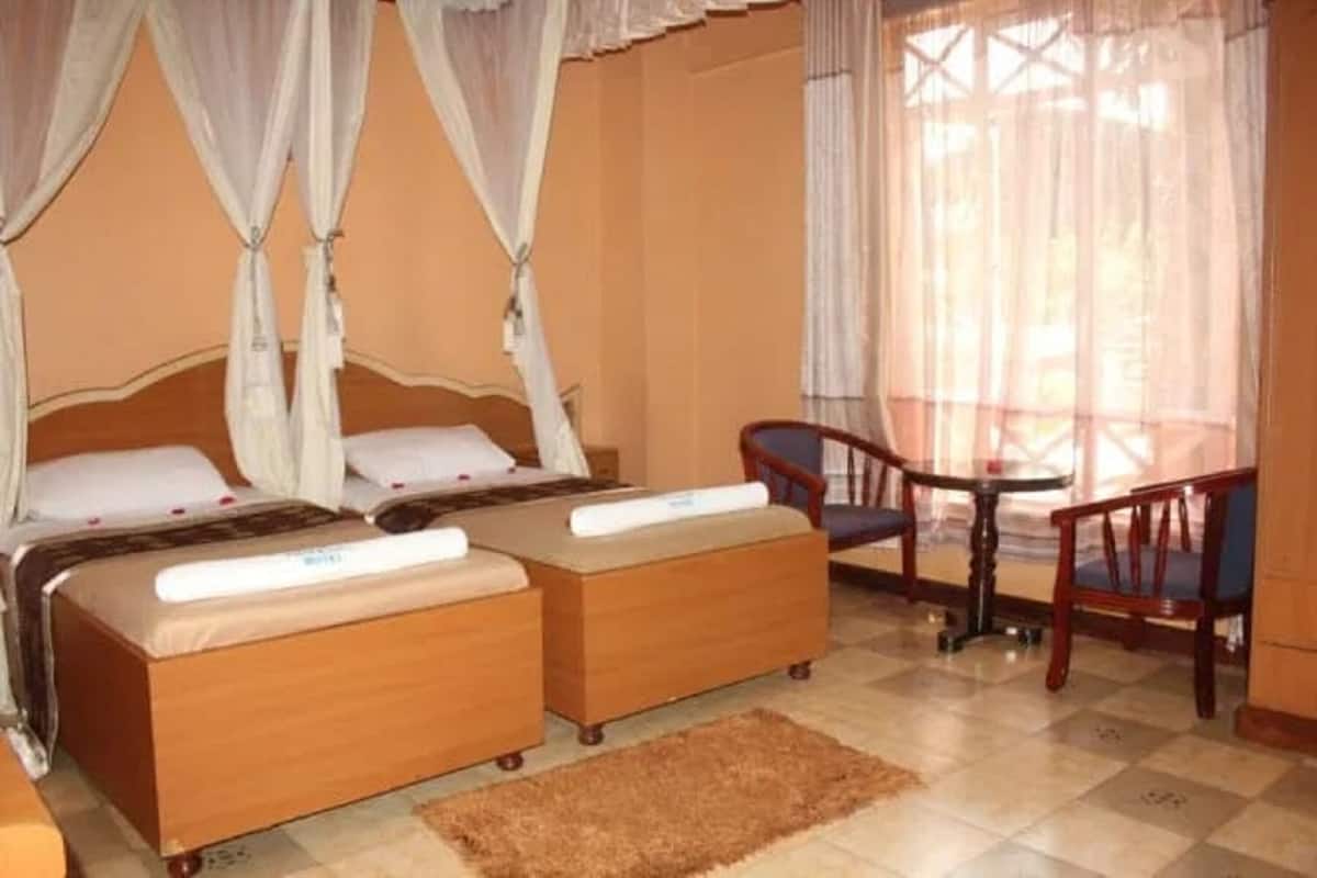 Une chambre avec deux lits, une petite table et une chaise.