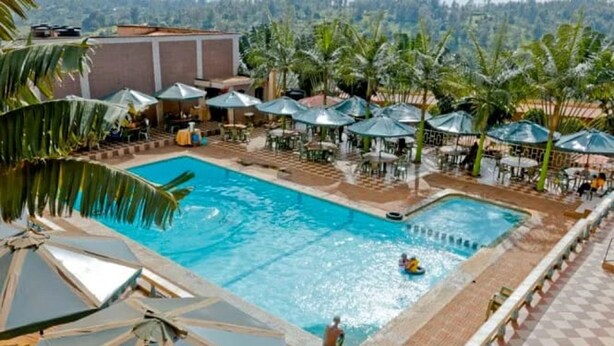 A pool area with umbrellas and lounge chairs, surrounded by palm trees.