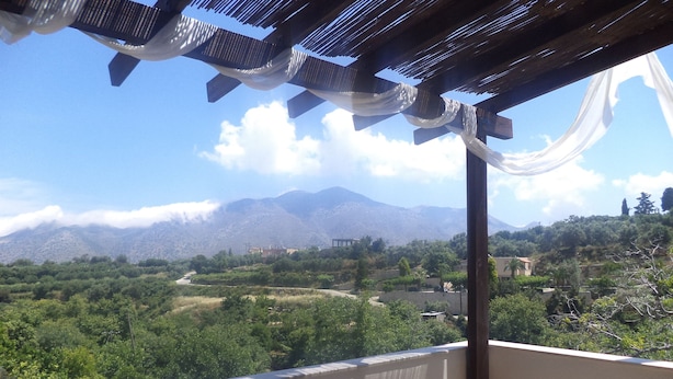 A balcony with a view of a mountainous landscape, wooden chairs, and a table. - Rural Spacious Villa with Pool at Central Crete (Mylopotamos)