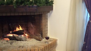 A fireplace with a fire, a glass of red wine, and an open book on the floor. - Rural Spacious Villa with Pool at Central Crete (Mylopotamos)