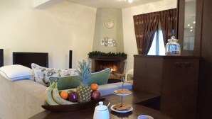 A cozy room with a bed, a dining table with fruit and mugs, a fireplace, and a cabinet. - Rural Spacious Villa with Pool at Central Crete (Mylopotamos)