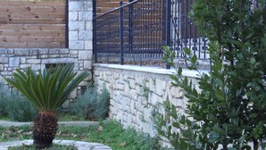 A stone wall with a metal gate, a palm tree, and a wooden fence in the background. - Rural Spacious Villa with Pool at Central Crete (Mylopotamos)