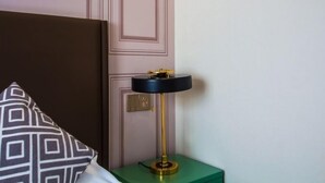 Une chambre avec un lit, une table de chevet verte et une lampe de table noire et dorée.