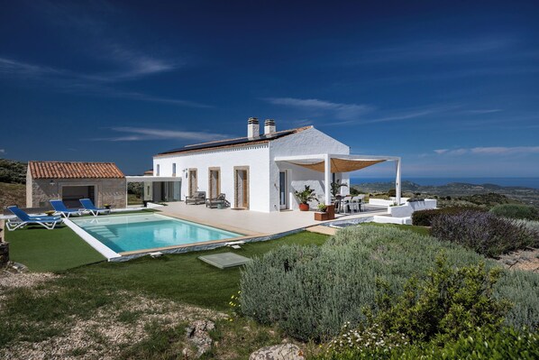 Una villa moderna con piscina, area salotto esterna e vista sul paesaggio.