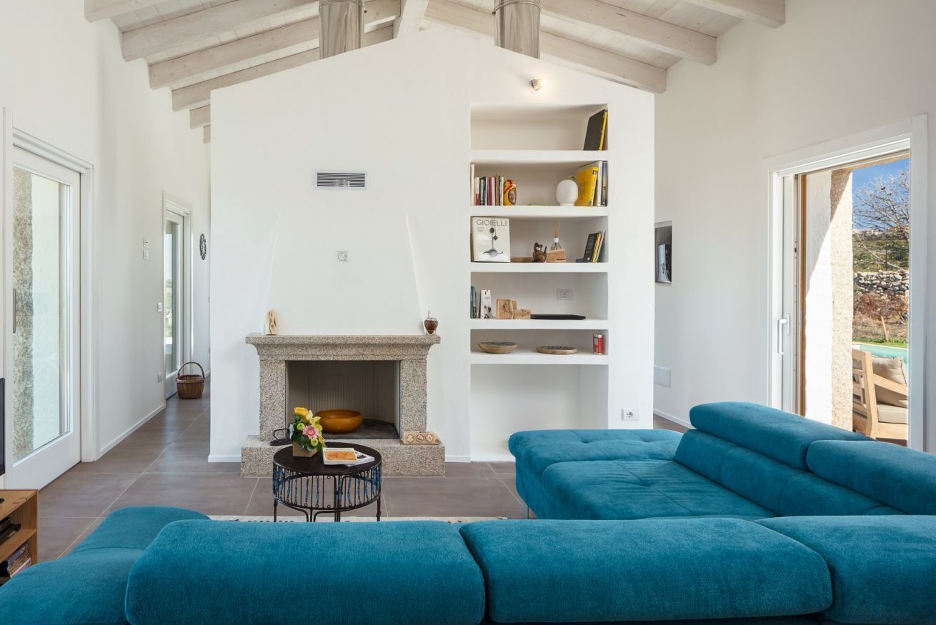 A modern living room with a fireplace, a blue sofa, and a bookshelf.