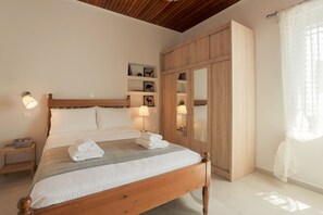 A neatly made bed with a wooden headboard, bedside lamps, and a large wardrobe with a mirror.