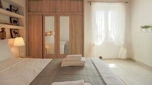 Ein Schlafzimmer mit einem Bett, einem Holzschrank, einem Nachttisch mit Lampe und einem Fenster mit Vorhängen.