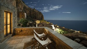 Un bâtiment en pierre doté d’un balcon donnant sur une falaise et la mer.