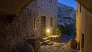 Un bâtiment en pierre doté d’une entrée rustique, d’un petit jardin et offrant une vue sur un paysage montagneux.