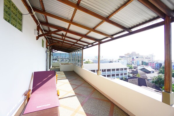 Un balcón con vistas a un paisaje urbano, una colchoneta de yoga y una ventana con marco de metal.