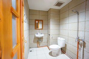 A bathroom with a toilet, sink, mirror, and shower.
