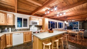 A spacious kitchen with wooden cabinets, a large island with stools, a microwave, and a stove. - 66SL - Hot Tub - WiFi - 3+ Bedroom - Sleeps 10 Home by RedAwning (Deming)