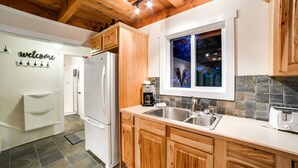 A kitchen with wooden cabinets, a white refrigerator, a double sink, and a coffee maker. - 66SL - Hot Tub - WiFi - 3+ Bedroom - Sleeps 10 Home by RedAwning (Deming)