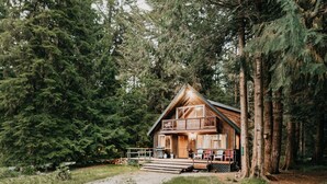 Une cabane en bois dotée d’un balcon, entourée d’une forêt dense.